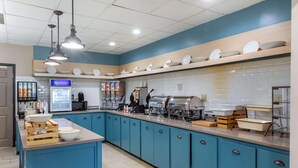 A kitchen with blue cabinets, a central island, and various appliances including a microwave, coffee machine, and toaster. - Country Inn & Suites by Radisson, Atlanta Downtown (Atlanta)