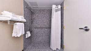 Un área de ducha moderna con pared de azulejos, un toallero de metal con toallas dobladas y una cortina de ducha.