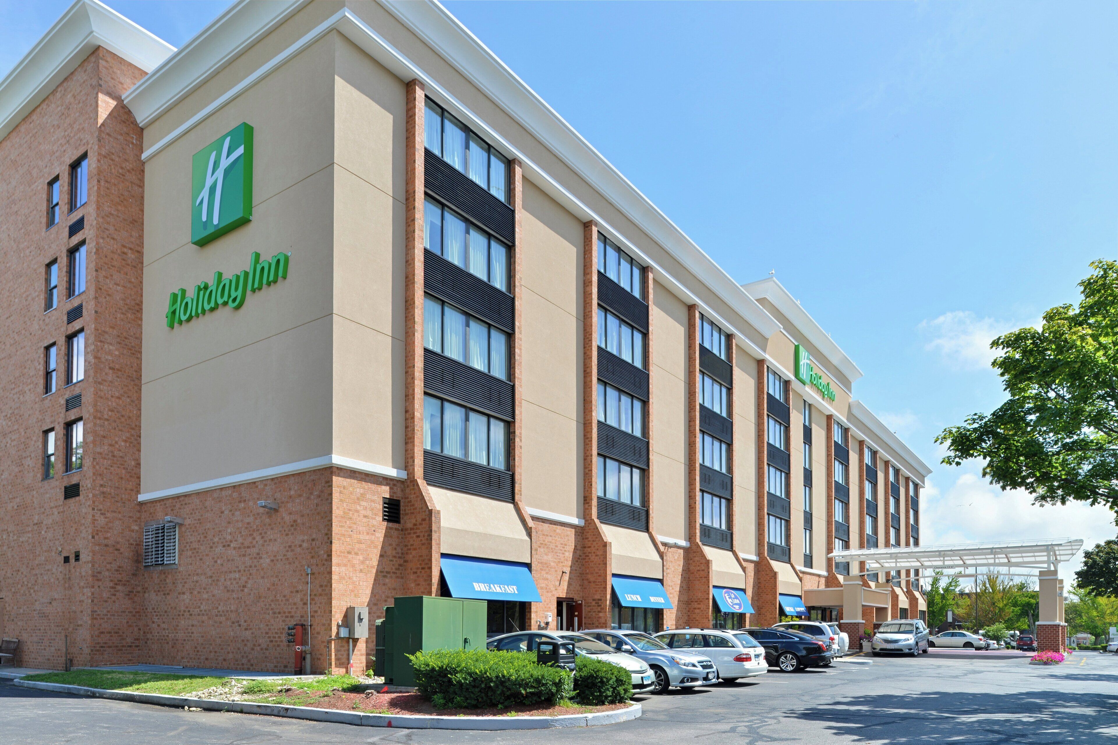 A Holiday Inn Express hotel with a brick facade, multiple windows, and a parking lot with several cars.