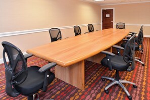 A conference room with a long wooden table, black office chairs, and a patterned carpet. - Holiday Inn New London - Mystic Area by IHG (New London)