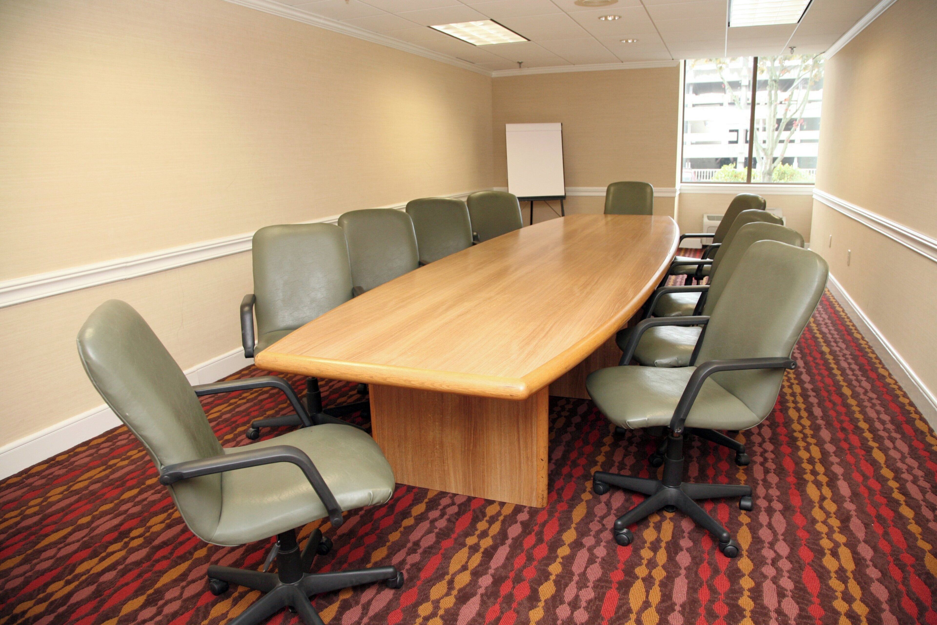 A conference room with a long table, green chairs, and a whiteboard.
