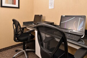 Un espacio de trabajo en un hotel con dos computadoras portátiles HP, una impresora y dos sillas de oficina.