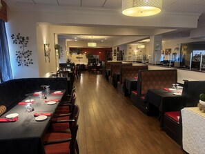 A restaurant with booths and tables, wooden flooring, and a modern interior design. - Holiday Inn New London - Mystic Area by IHG (New London)
