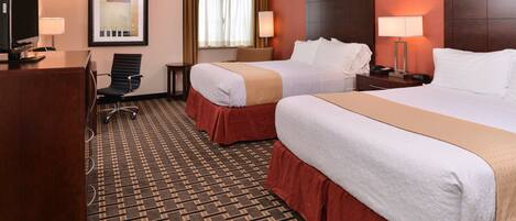 A hotel room with two beds, a desk, a chair, and a television.