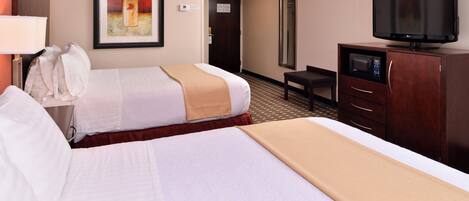 A hotel room with two beds, a television, a desk, and a chair.