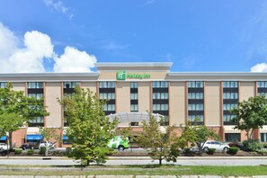 A Holiday Inn hotel with a modern facade, multiple windows, and a parking lot with several cars. - Holiday Inn New London - Mystic Area by IHG (New London)