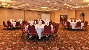 A conference room with round tables, red chairs, and white tablecloths. - Holiday Inn New London - Mystic Area by IHG (New London)