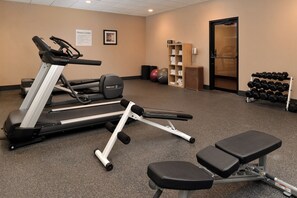 A fitness center with cardio equipment, dumbbells, and a bench. - Holiday Inn New London - Mystic Area by IHG (New London)