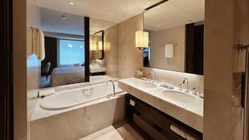 Uma casa de banho moderna com duas pias, um espelho grande e vista para um quarto.