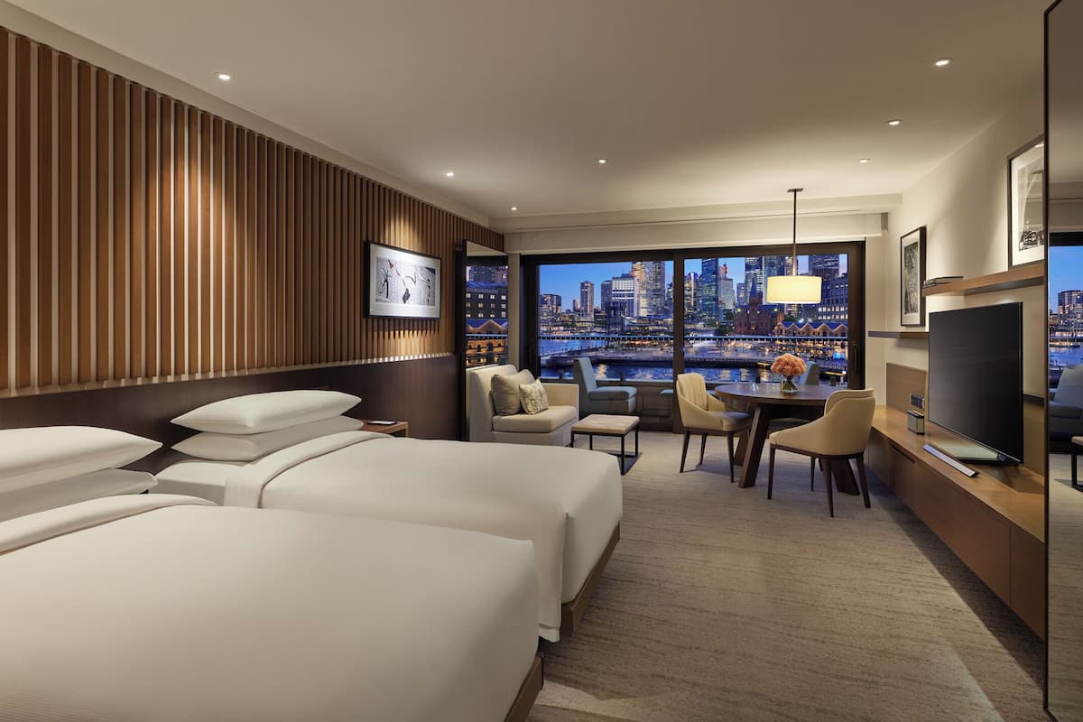 A hotel room with a city view, a large bed, a desk, and a television.
