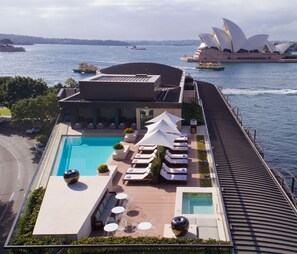 Relax by the rooftop pool surrounded by lounge chairs and sunbeds, with stunning views of the Sydney Opera House.