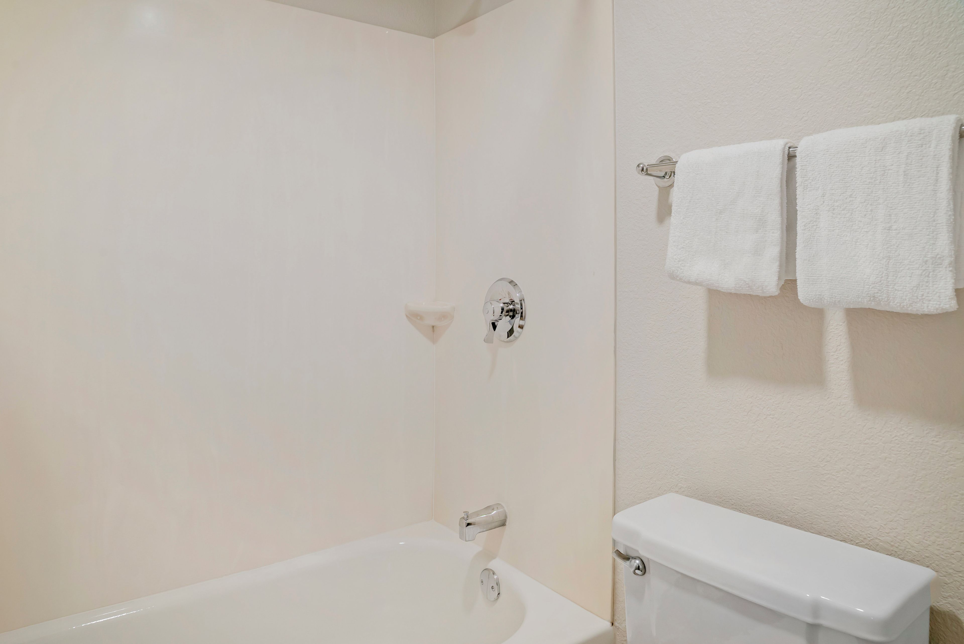 Un baño con una bañera blanca, un inodoro y un perchero con dos toallas.