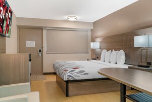 Una habitación de hotel con cama, mesitas de noche, escritorio y televisor.