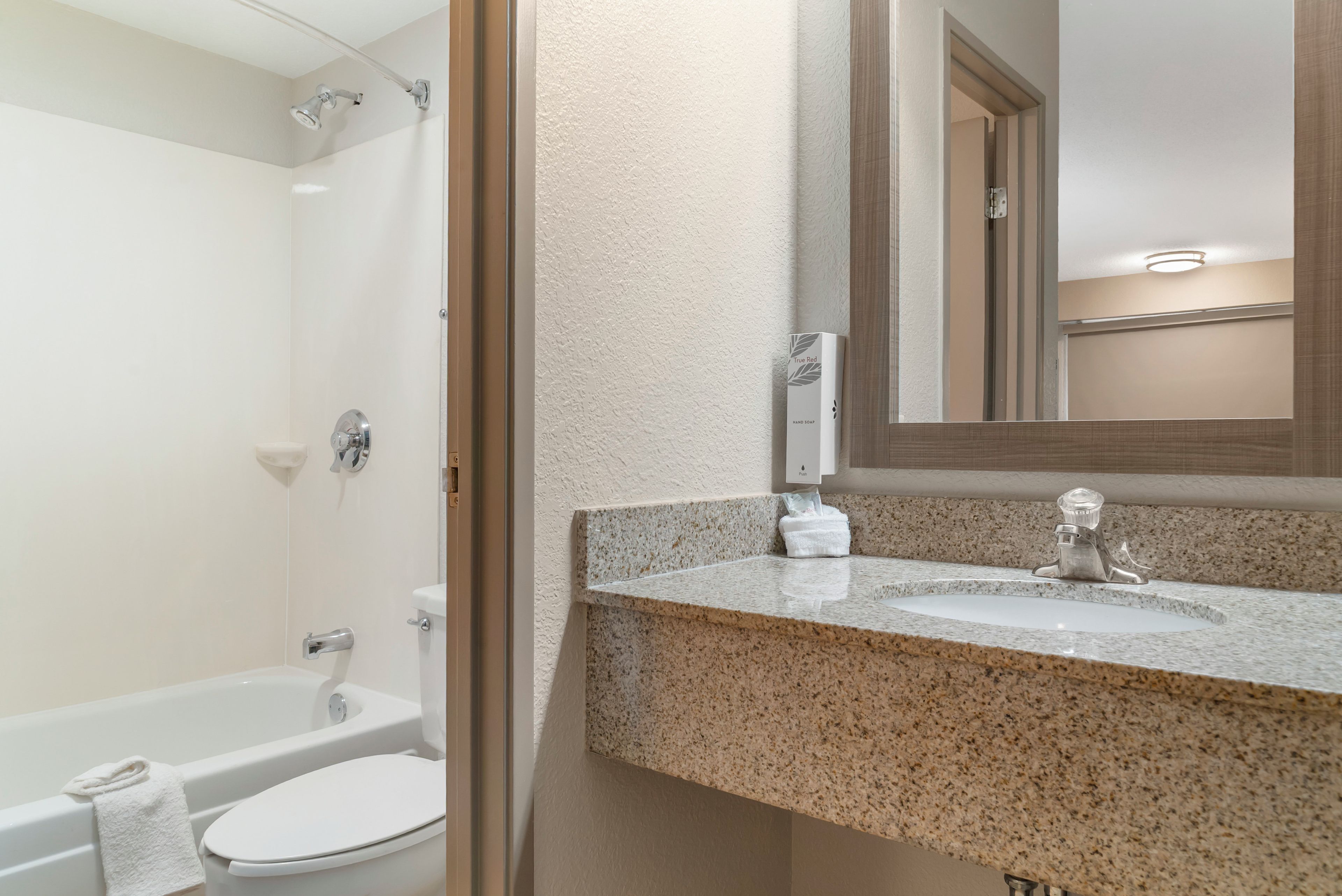 Un baño con bañera, inodoro y encimera de granito con grifo.