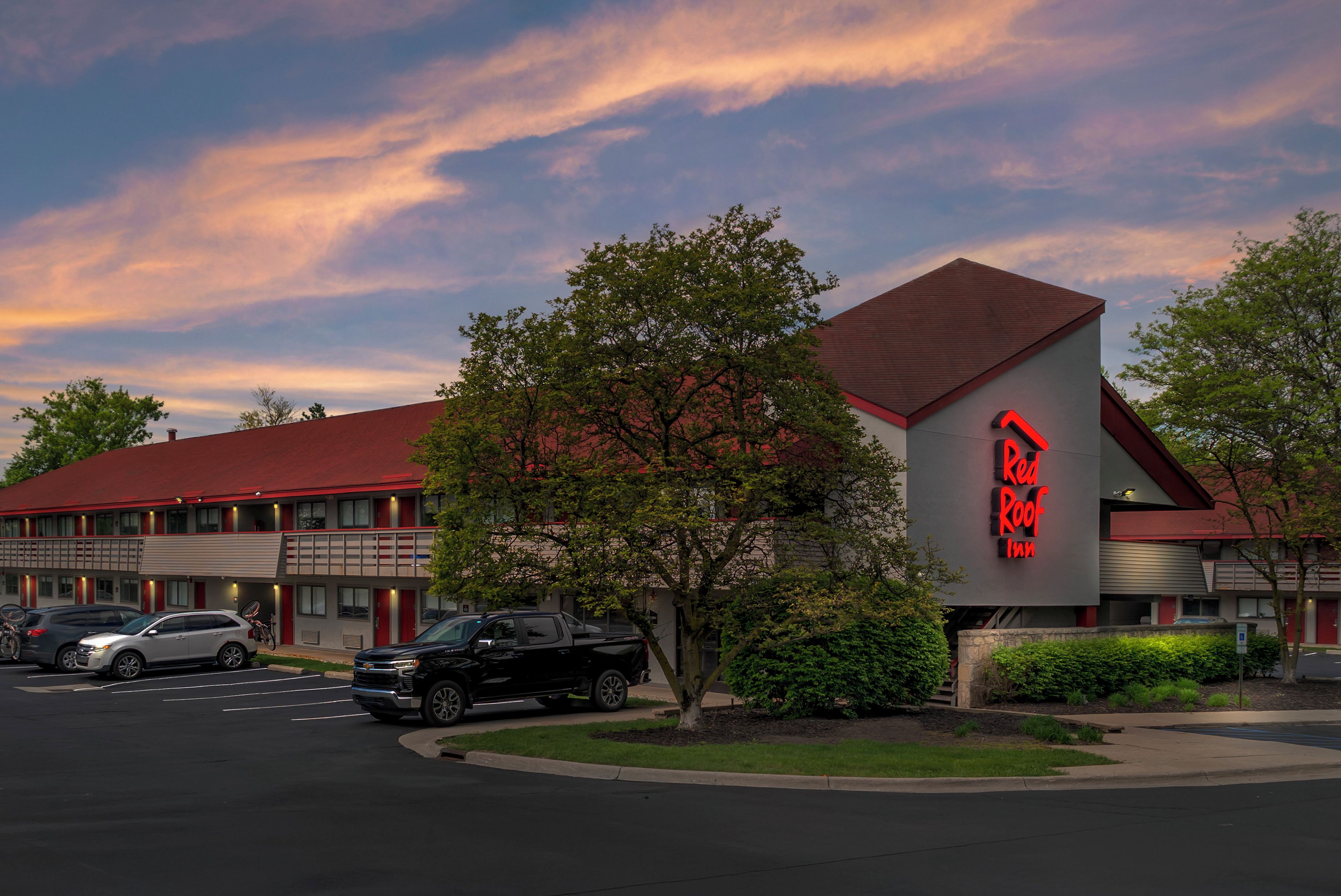 Un Red Roof Inn con techo rojo, estacionamiento y cielo despejado.