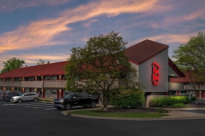 A Red Roof Inn with a red roof, a parking lot, and a clear sky.