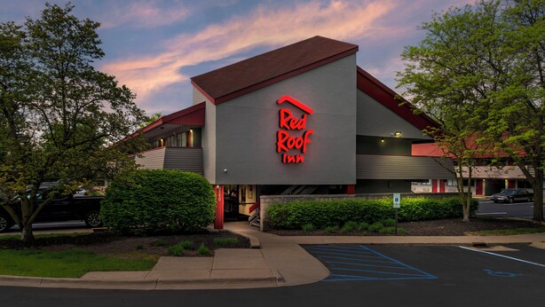 Un hotel Red Roof Inn con un diseño arquitectónico moderno, que destaca por su techo rojo y señalización.