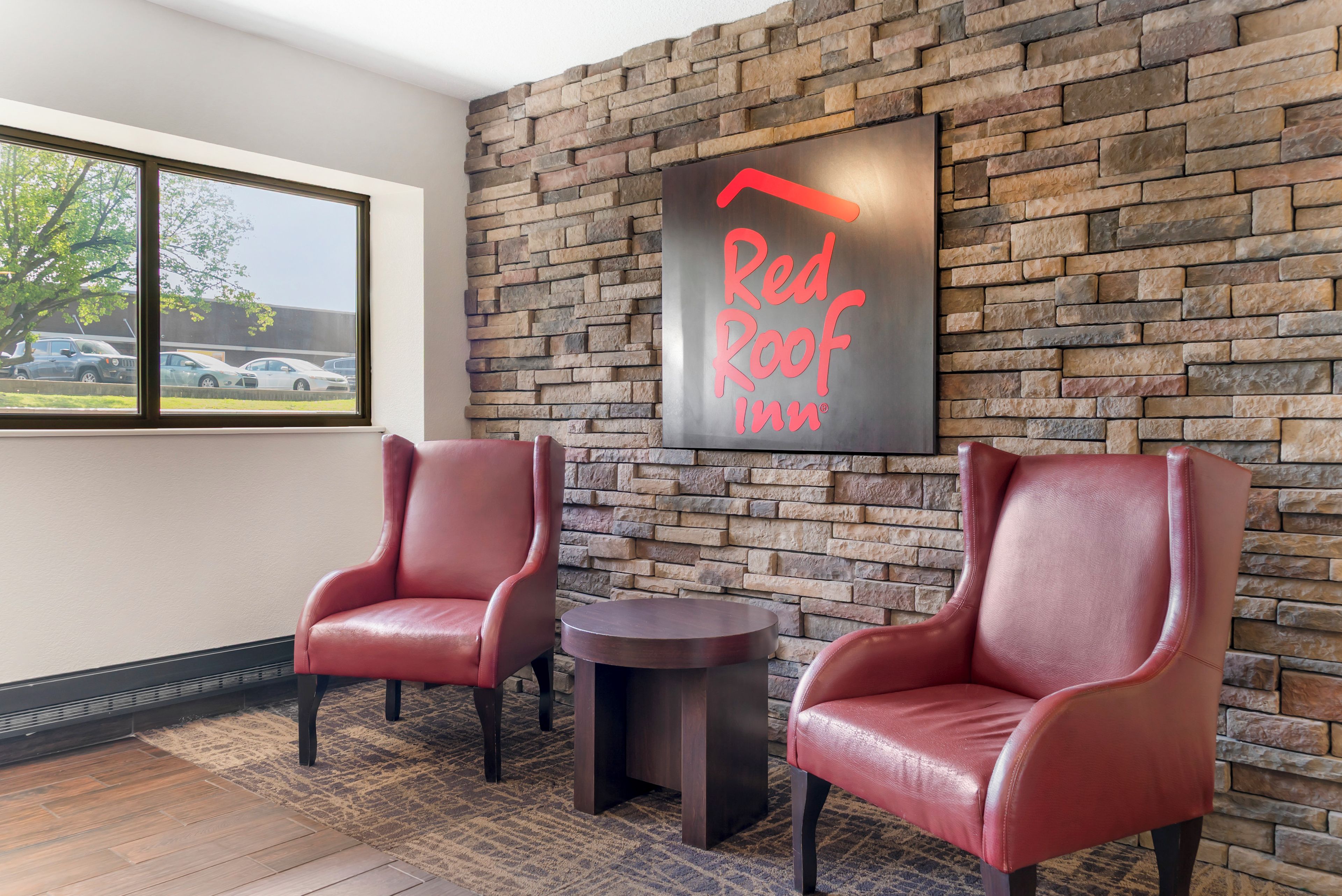 Hall del Red Roof Inn con due poltrone in pelle, un tavolino rotondo e un muro in pietra.