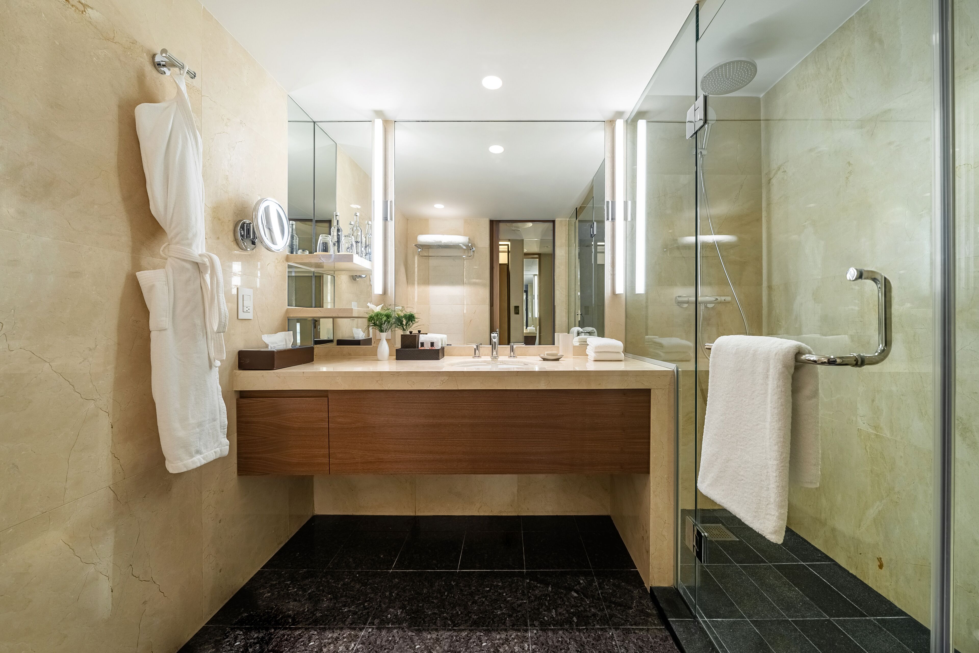 A modern bathroom with a large mirror, a vanity with a sink, a glass shower enclosure, and a towel rack.