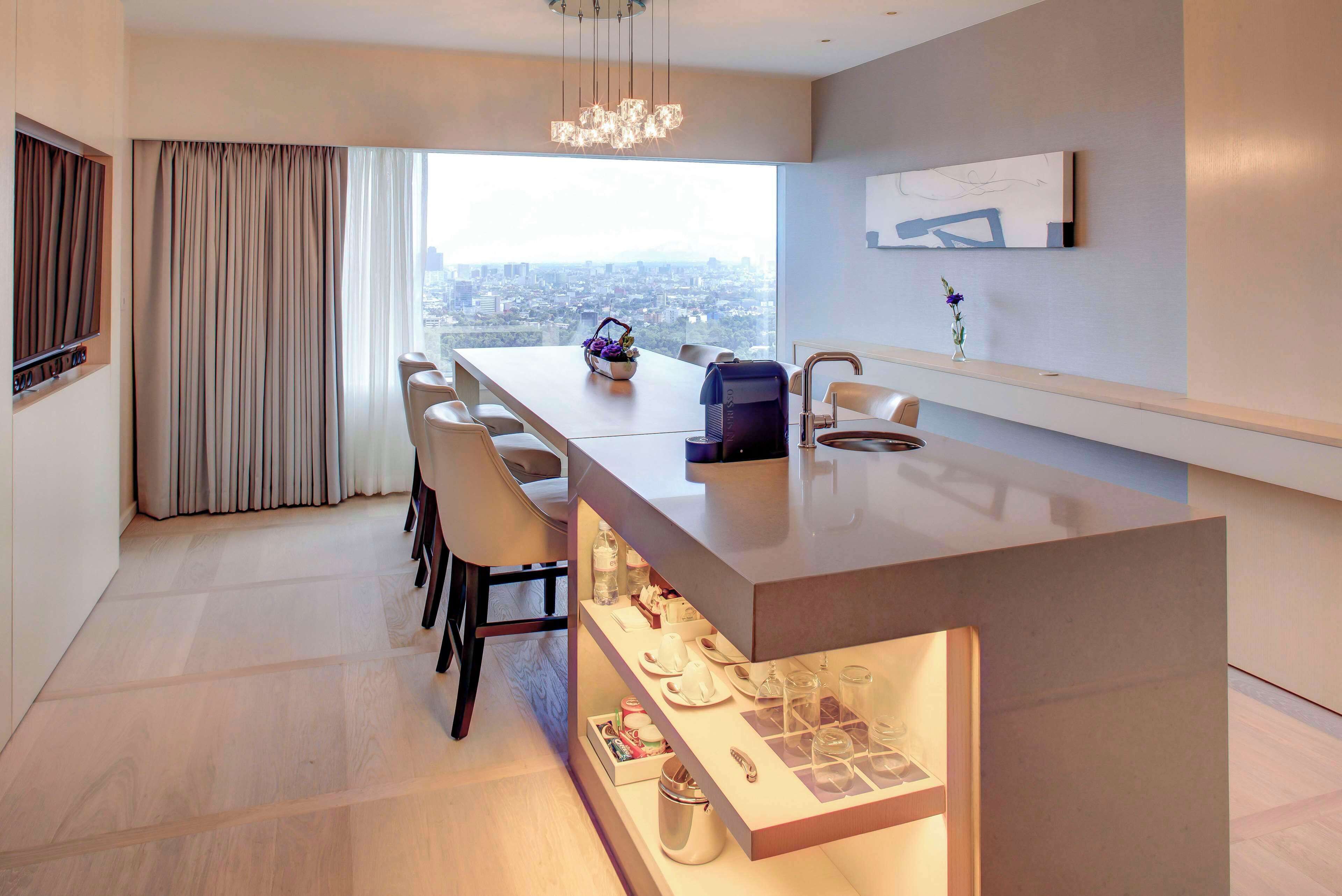 Un comedor moderno con una mesa larga, sillas y una encimera de cocina integrada.