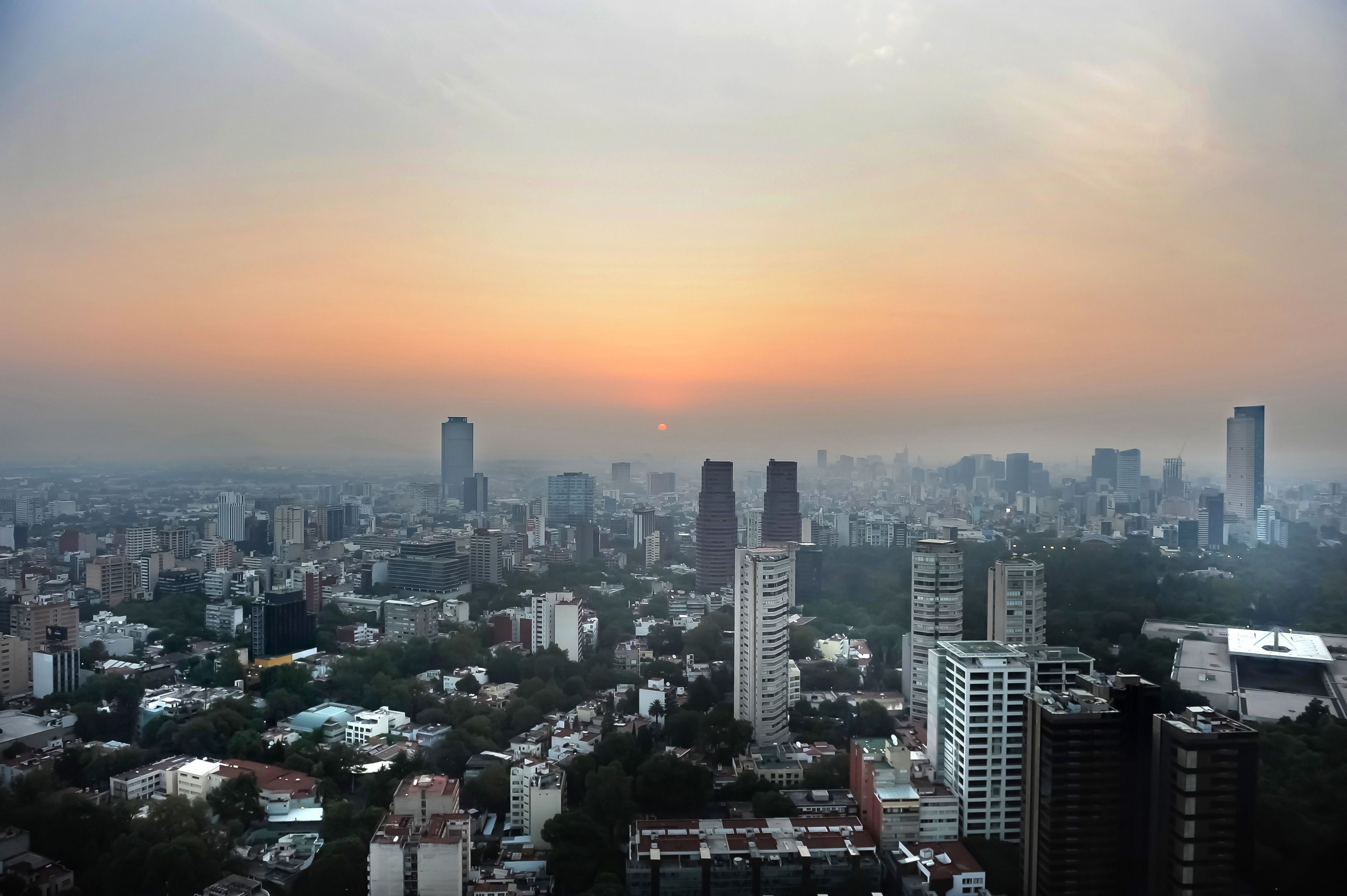 Un paisaje urbano con rascacielos y un atardecer.