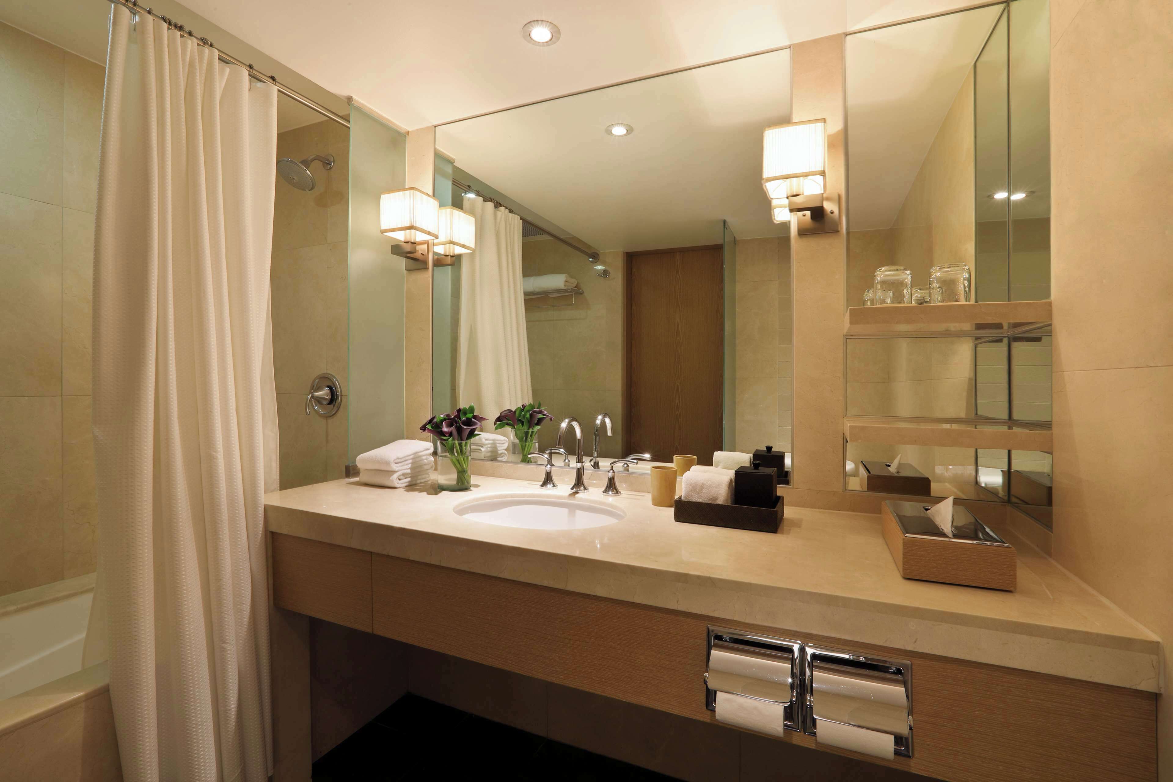 A modern bathroom with a large mirror, a sink, and a shower.