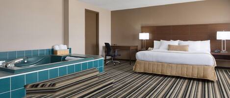 A hotel room with a large bed, a bathtub, a desk, and a chair.
