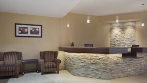 A reception area with a stone wall, two striped armchairs, a small table, and pendant lighting. - Days Inn by Wyndham Dalhousie (Dalhousie)