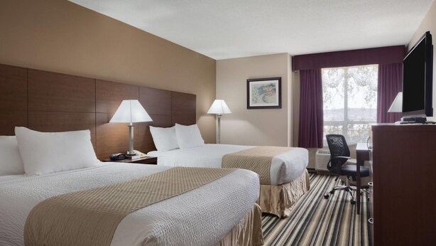 A hotel room with two beds, a desk, a chair, and a television. - Days Inn by Wyndham Dalhousie (Dalhousie)
