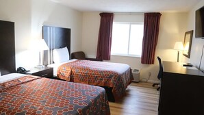 Una habitación de hotel con dos camas, un escritorio, una silla, un televisor y una ventana con cortinas.
