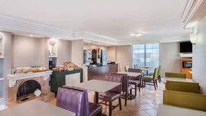 A modern restaurant with a bar area, seating, and a fireplace. - Baymont by Wyndham Fort Myers Central (Fort Myers)
