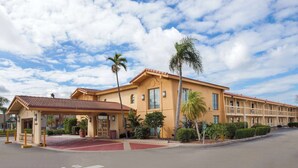 A hotel with a red-tiled roof, a covered entrance, and a parking lot. - Baymont by Wyndham Fort Myers Central (Fort Myers)