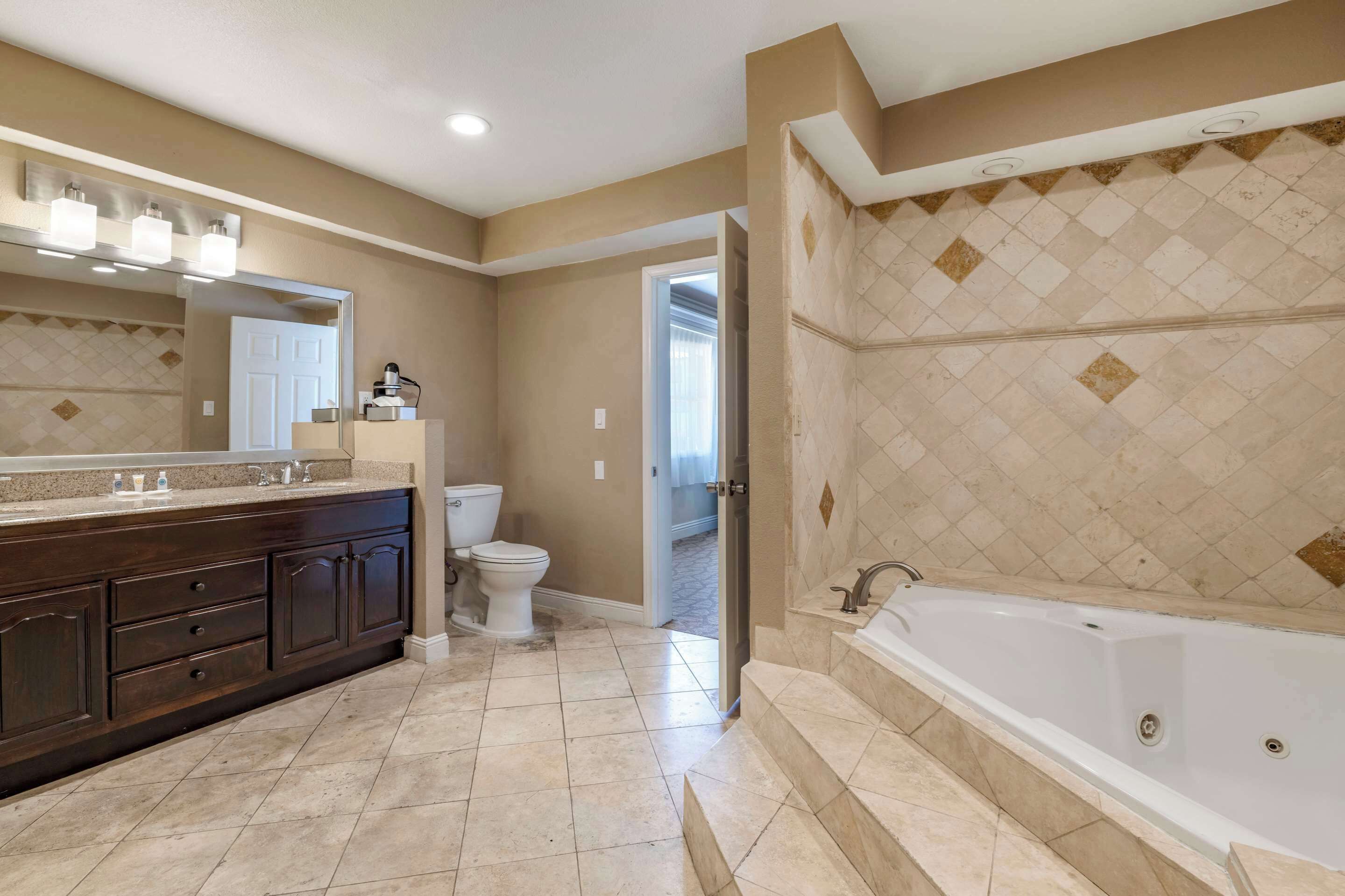 A modern bathroom with a large bathtub, a dark wooden vanity, and a toilet.