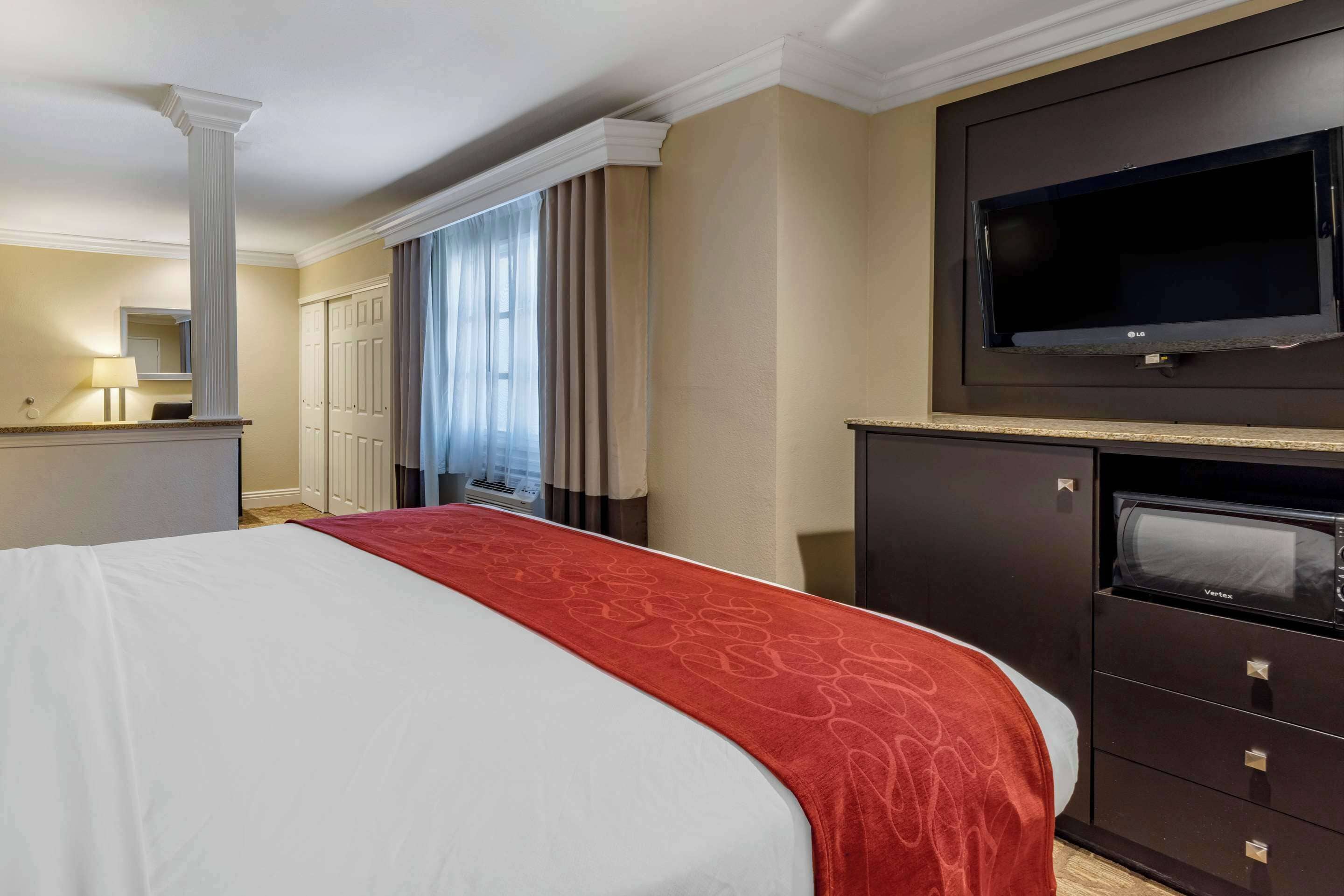 Une chambre d’hôtel avec un grand lit, un téléviseur à écran plat, un four à micro-ondes et une commode.