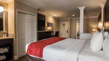 Habitación de hotel con una cama grande, un escritorio, una silla, un televisor y un baño.