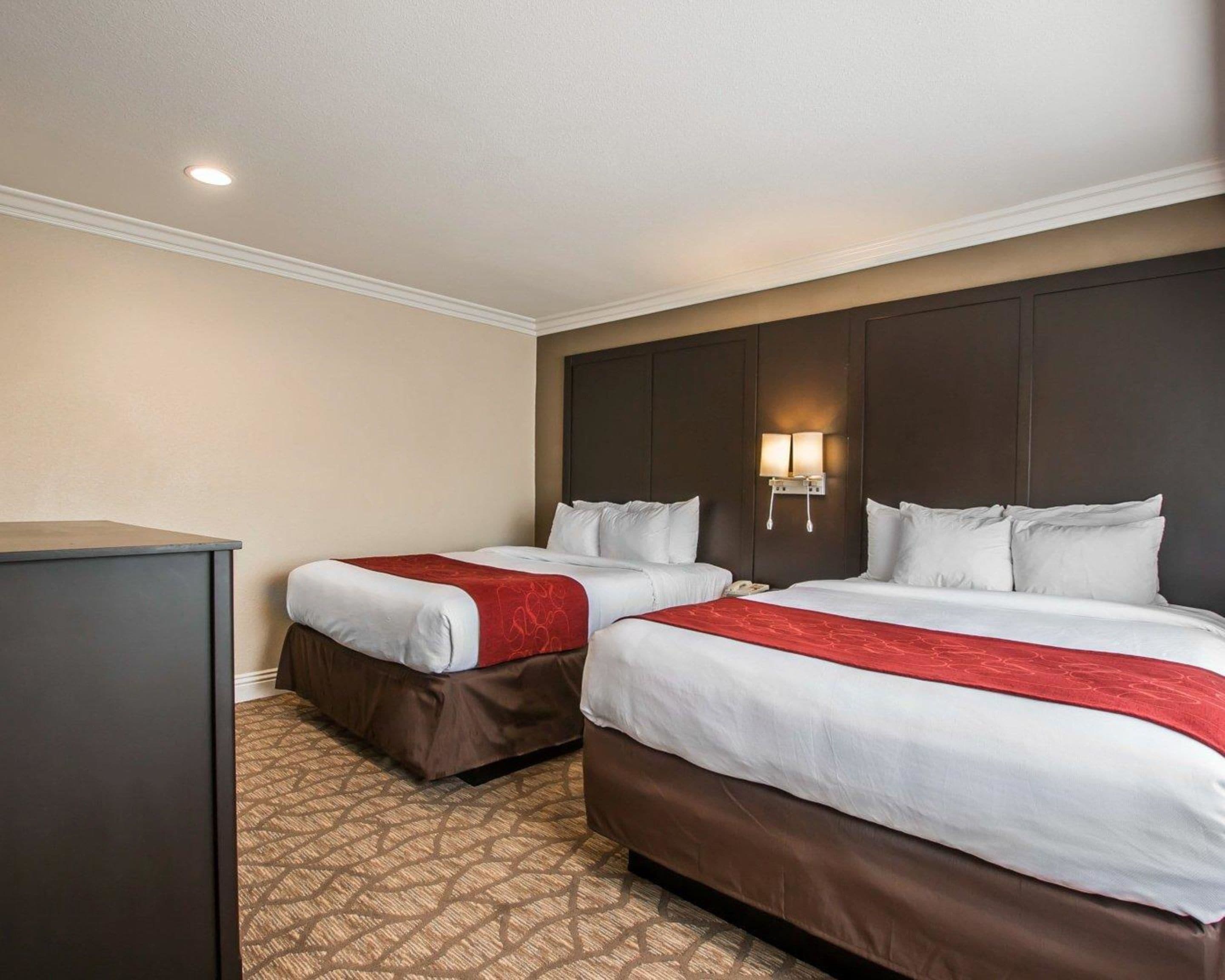 A hotel room with two beds, a desk, and a nightstand.