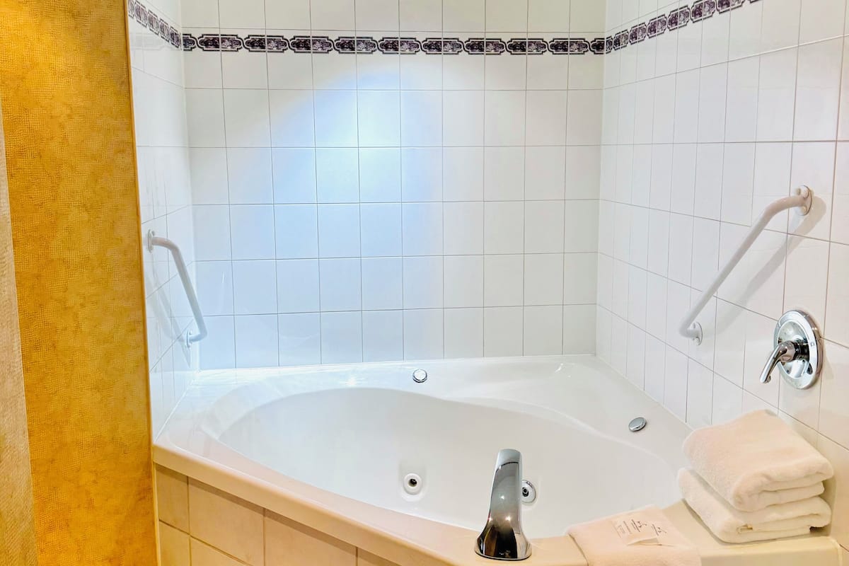 Une salle de bain moderne avec une baignoire sur pieds, un meuble-lavabo avec un miroir et un porte-serviettes.