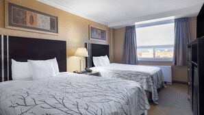 A hotel room with two beds, a large window with curtains, a flat-screen TV, and artwork on the walls. - Travelodge by Wyndham Prince Albert (Prince Albert)
