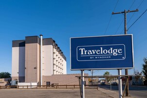 Señal de Travelodge frente a un edificio de diseño moderno.