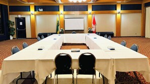 A conference room with a long table, chairs, a projector screen, and flags. - Travelodge by Wyndham Prince Albert (Prince Albert)