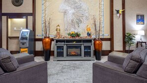 A lobby with a fireplace, two sofas, a reception desk, a clock, and a large wall mural. - Travelodge by Wyndham Prince Albert (Prince Albert)