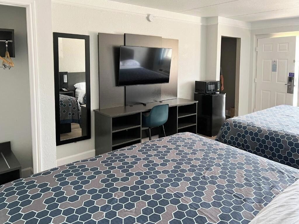 A hotel room with two beds, a TV, a desk, and a chair.