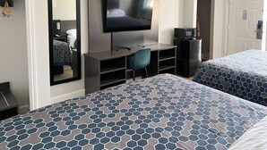 A hotel room with two beds, a TV, a desk, and a microwave.