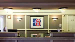 A reception desk with a framed sign for a motel, a clock, and a door marked "Employee Only".