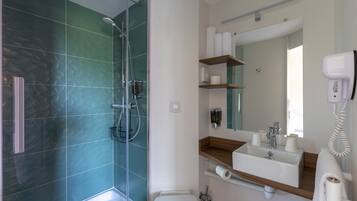 Een moderne badkamer met een douche met glazen wand, een houten wastafelmeubel met een spiegel en een wit toilet.