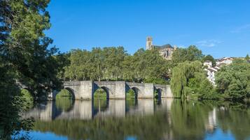 A stone bridge over a calm river with a church in the background.
