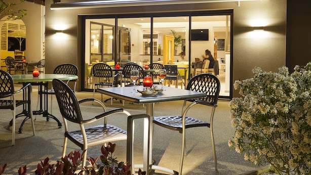 An outdoor seating area of Le Provençal with tables and chairs, and a visible entrance to the restaurant. - The Originals City Hotel Limoges Sud (Feytiat)