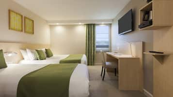 Habitación de hotel con dos camas, un escritorio, una silla, un televisor y obras de arte en la pared.