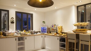 A modern kitchen with white cabinets, a wooden countertop, and a breakfast bar with seating. - The Originals City Hotel Limoges Sud (Feytiat)