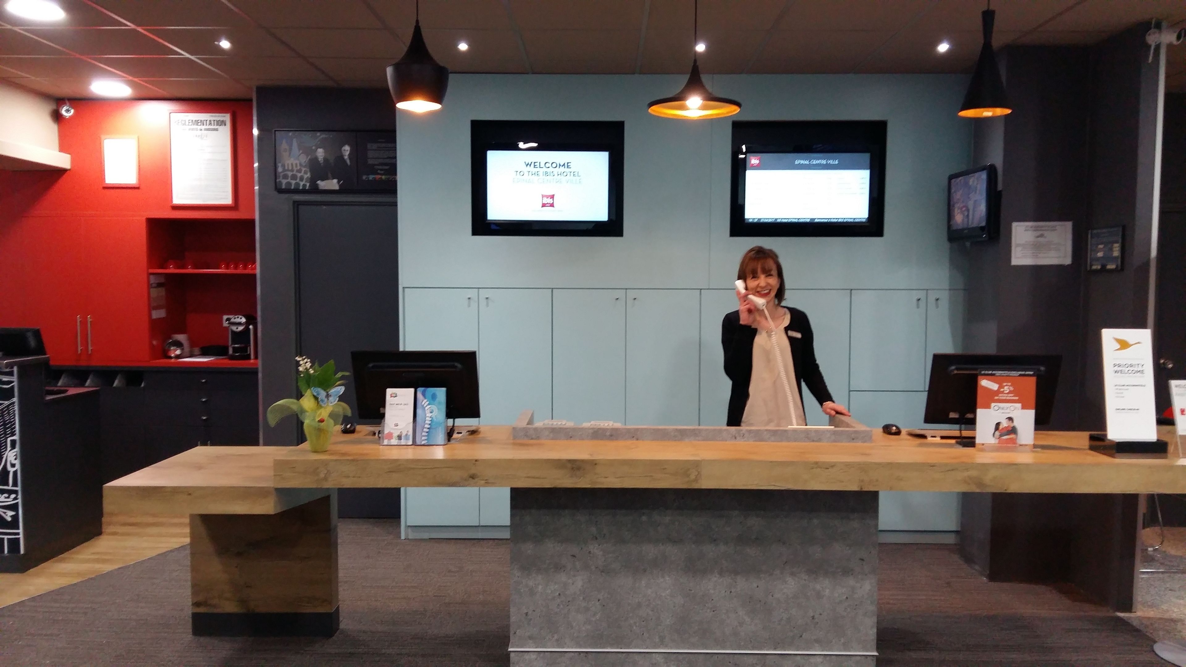 A reception desk with a modern design, featuring a wooden counter and a large screen displaying a welcome message.